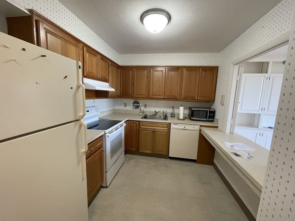 80 Salisbury Street, Unit 806 Worcester, MA 01609 - Photo 8 of 13 a kitchen with a sink a stove top oven a refrigerator and cabinets
