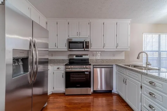 a kitchen with stainless steel appliances granite countertop a refrigerator sink and stove