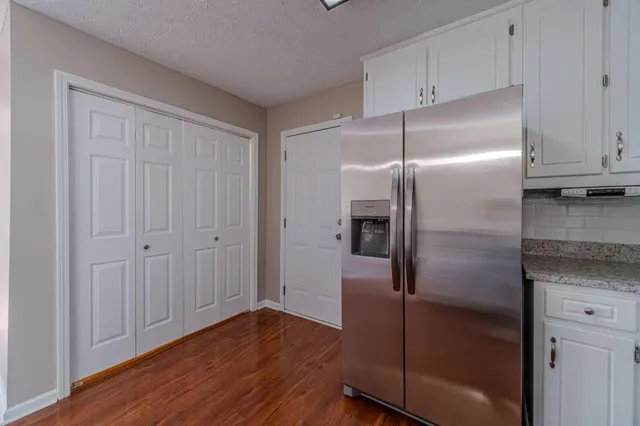 a kitchen with a refrigerator and wooden floor