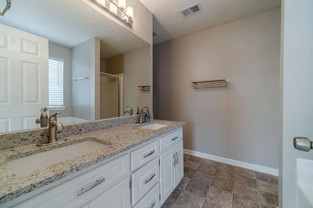 a bathroom with a granite countertop sink a mirror and a shower