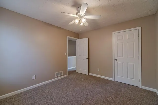 an empty room with a chandelier fan and windows
