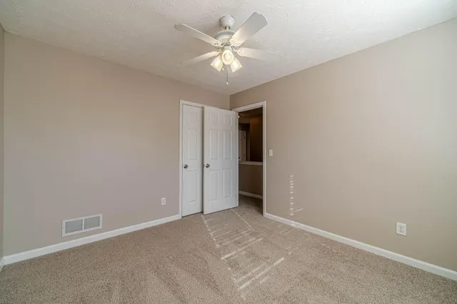 an empty room with a chandelier fan and windows
