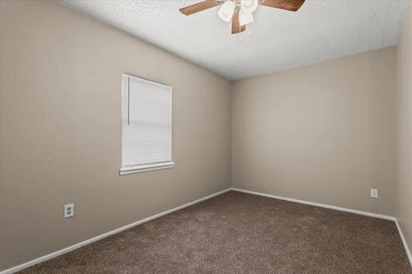an empty room with a chandelier fan and windows