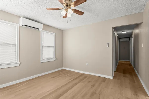 an empty room with wooden floor closet and windows