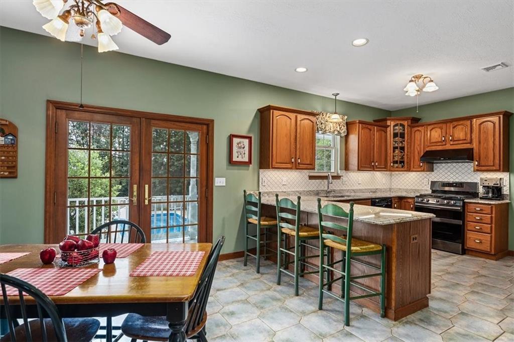 204 Salt Works Road Harmony, PA 16037 - Photo 11 of 35 a kitchen with stainless steel appliances granite countertop a stove a refrigerator a kitchen island a table and chairs in it