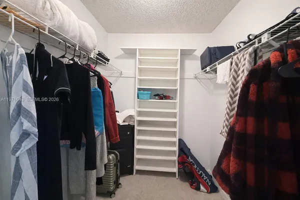 a view of walk in closet with clothes and shoes