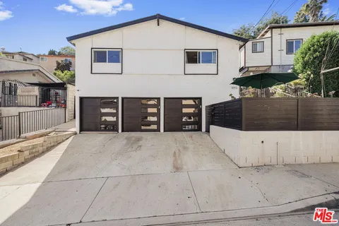 a view of a white house with a large space in front of it