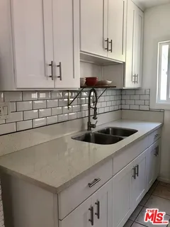 a kitchen with stainless steel appliances a sink a stove and white cabinets