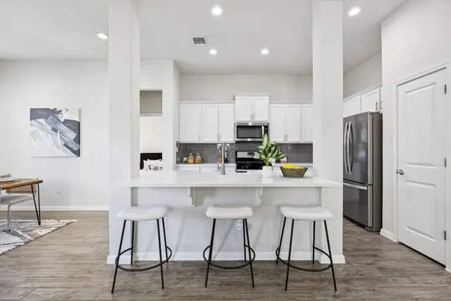 a kitchen with stainless steel appliances a table chairs refrigerator and wooden cabinets
