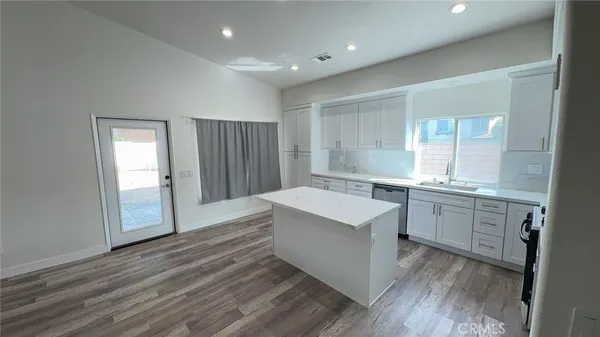 a hall with kitchen island white cabinets and wooden floor