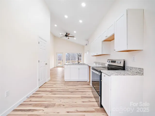 a kitchen with granite countertop a white stove top oven and white cabinets