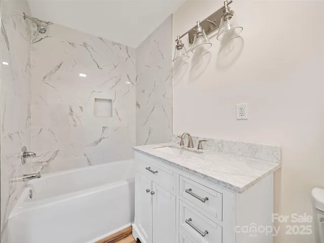 a bathroom with a granite countertop sink a toilet and bathtub