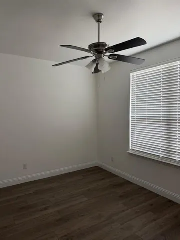 a view of a room with wooden floor a ceiling fan and a window
