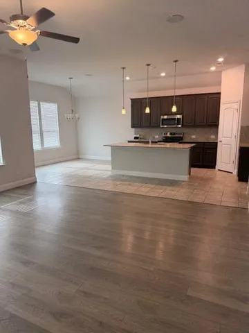 a view of kitchen with kitchen island granite countertop a stove top oven a sink and a counter top space