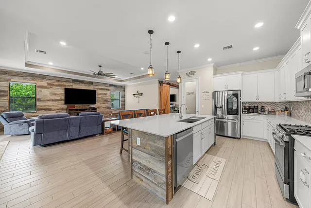 a kitchen with stainless steel appliances a stove a sink a refrigerator and a couch