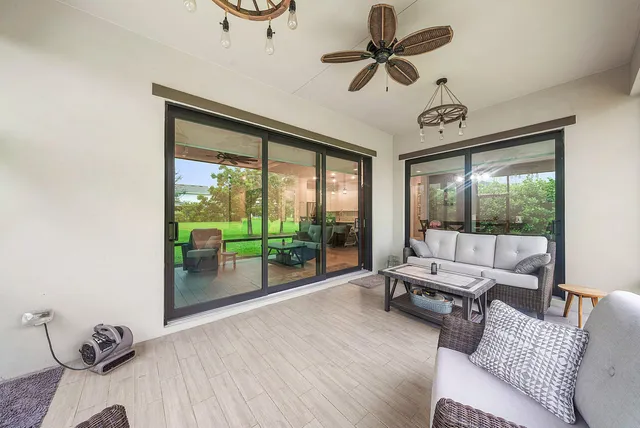 a living room with furniture large windows and wooden floor