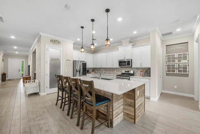 a kitchen with a dining table chairs wooden floor appliances and cabinets