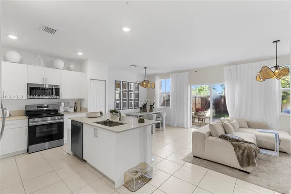 a kitchen with stainless steel appliances granite countertop a stove top oven a sink dishwasher a dining table and chairs with wooden floor