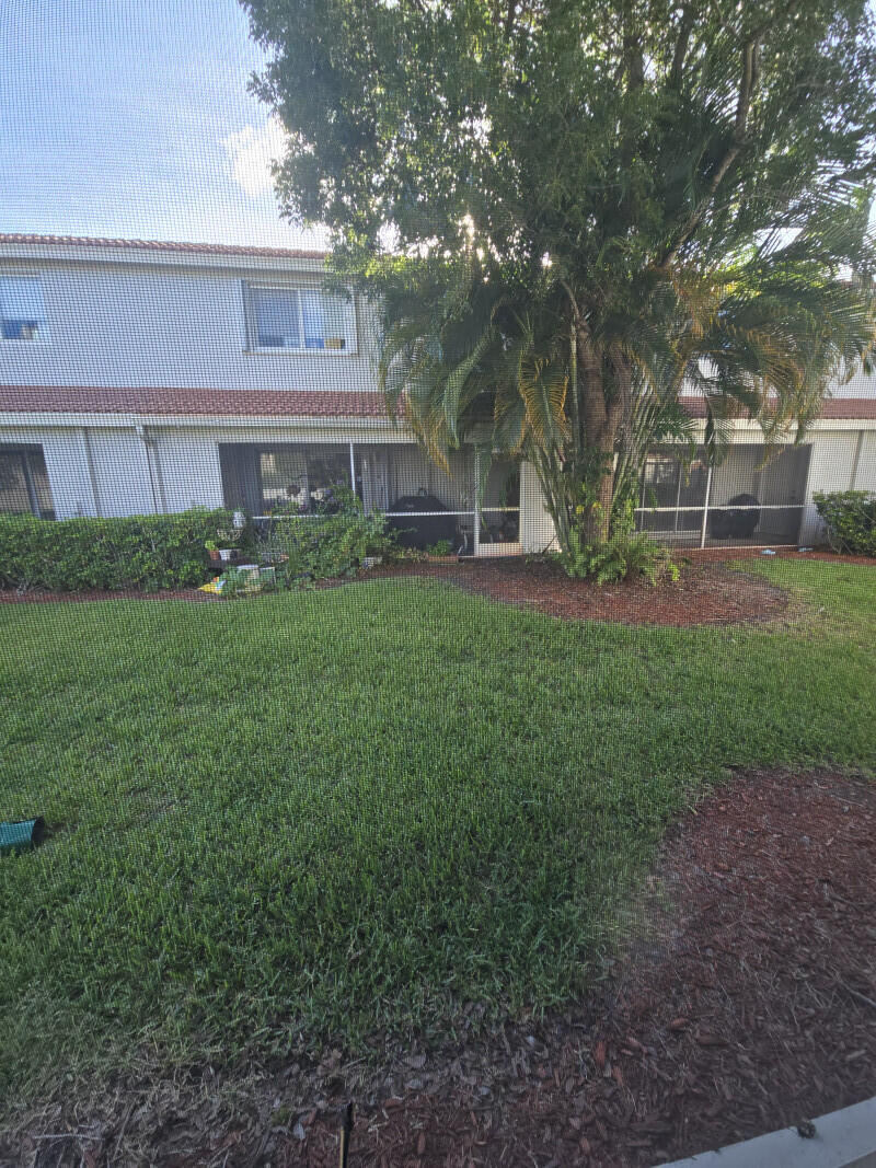 6511 Sandy Bank Terrace Riviera Beach, FL 33407 - Photo 2 of 12 a view of a big yard in front of a brick house with large windows
