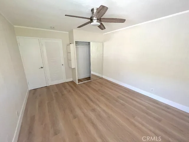 a view of a room with wooden floor and a ceiling fan
