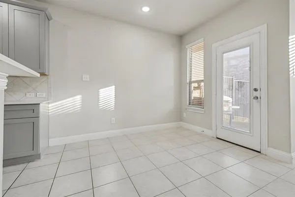 a view of an empty room with window and cabinet area