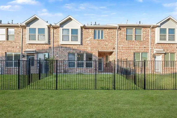 a view of a brick house with a small yard and a plant