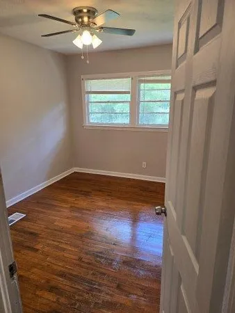 a view of empty room with wooden floor and fan