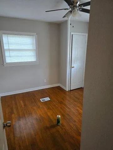 a view of an empty room with wooden floor and a window