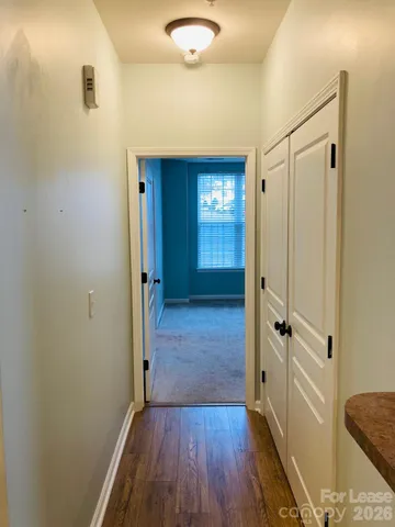 a view of a hallway with wooden floor and closet area