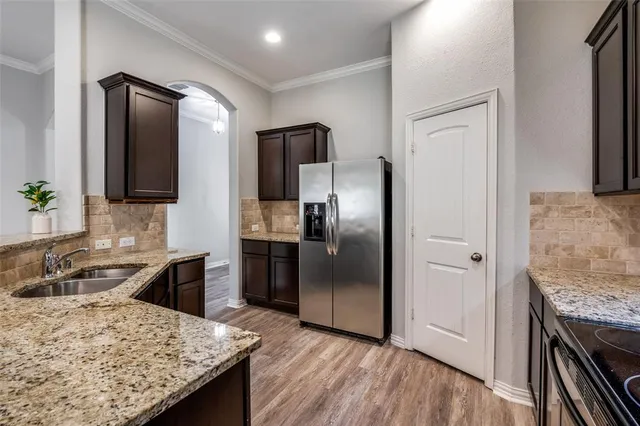 a kitchen with granite countertop a refrigerator and a sink
