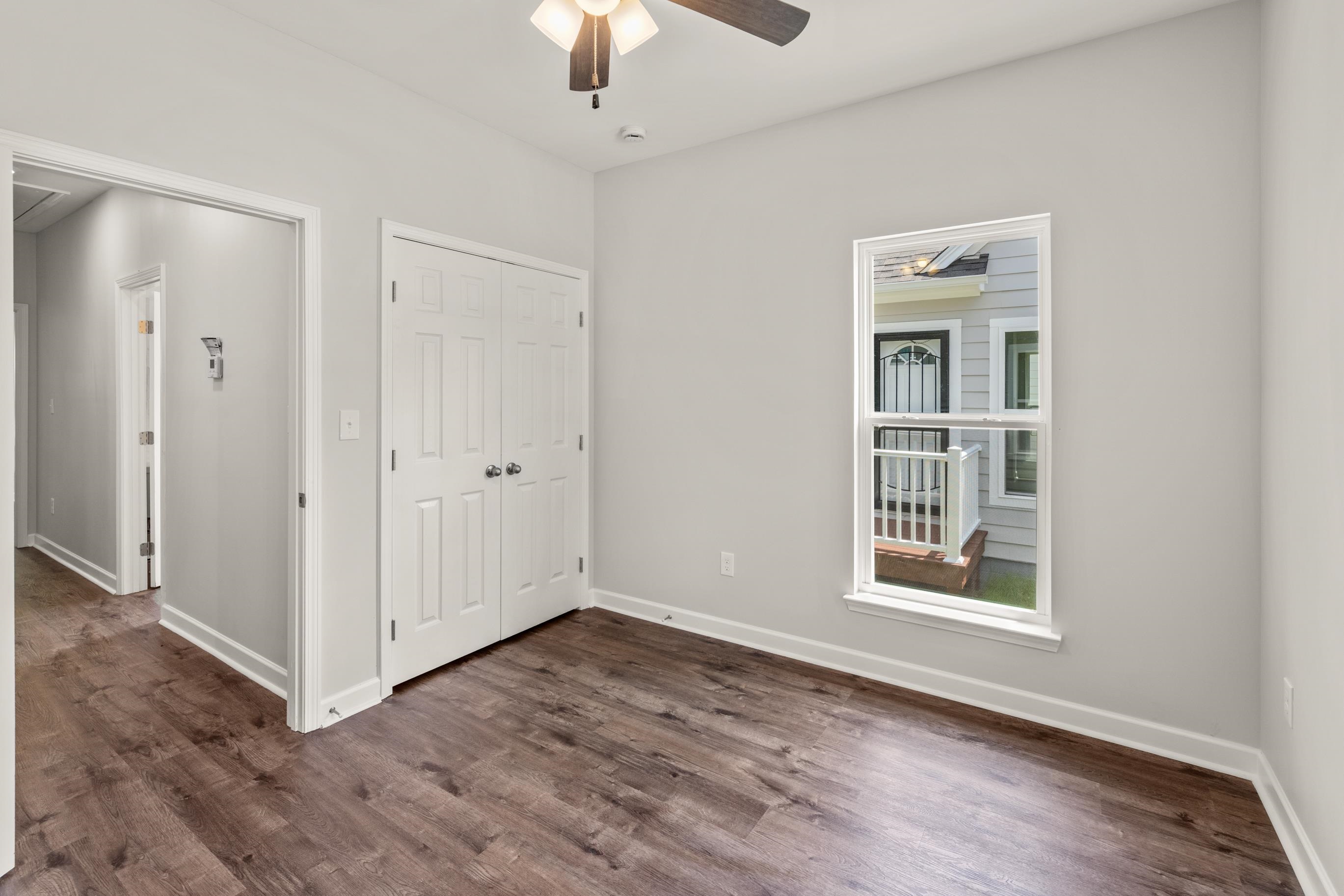 a view of an empty room with a window and wooden floor