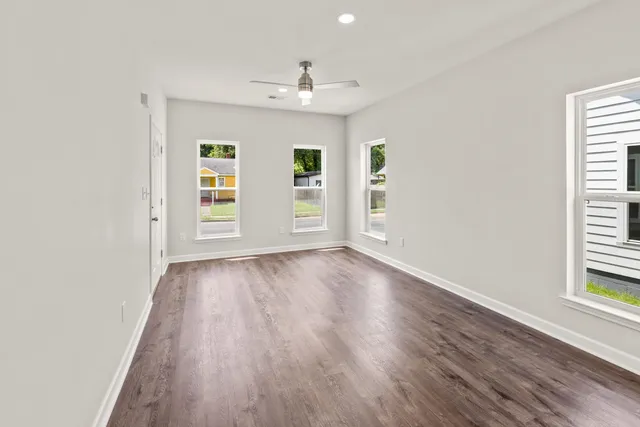 an empty room with wooden floor and windows