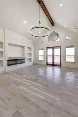a view of an empty room with window and wooden floor