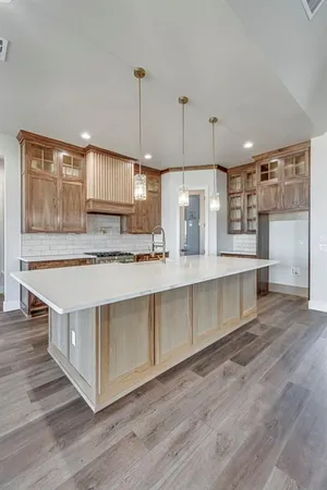a large kitchen with kitchen island a large counter top and stainless steel appliances