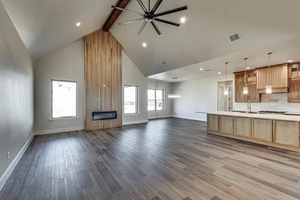 a view of an empty room with window and wooden floor