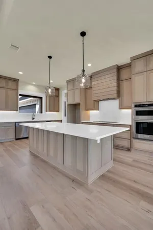 a large kitchen with stainless steel appliances kitchen island granite countertop a sink a counter space and cabinets