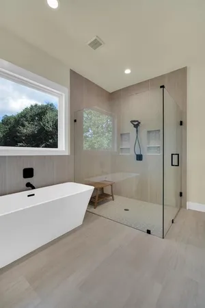 a bathroom with a tub a window and a shower