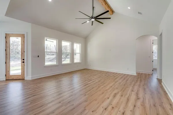an empty room with wooden floor fan and windows