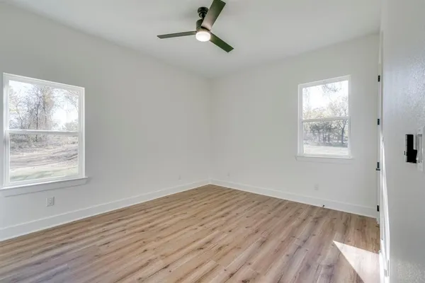 a view of empty room with wooden floor and fan