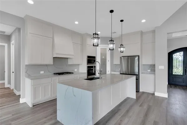 a kitchen with a refrigerator a stove top oven a counter space and wooden floor