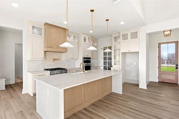 a large kitchen with stainless steel appliances granite countertop a stove a sink a refrigerator and a dining table with wooden floor