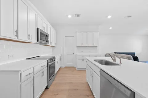 a kitchen with white cabinets sink and stove