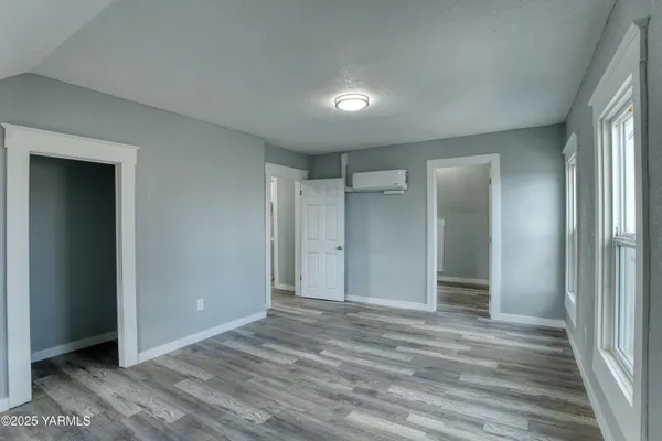 a view of empty room with wooden floor and fan