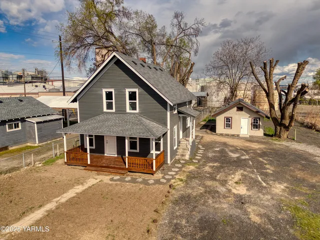 a view of a house with a yard and large tree