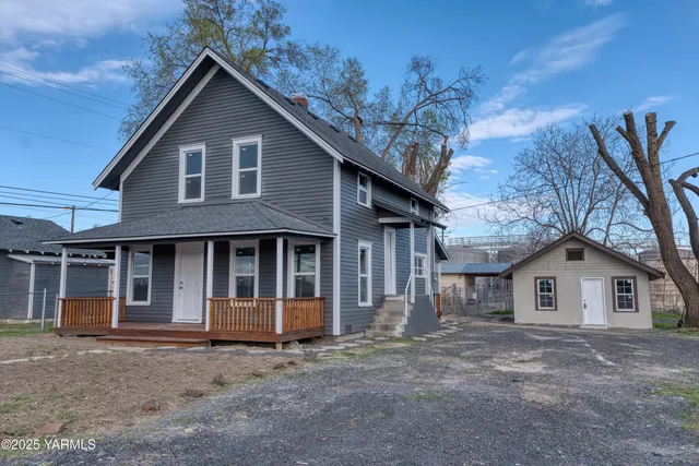 a view of a house with a yard and large tree