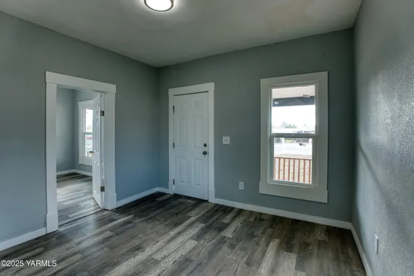 a view of empty room with wooden floor and fan
