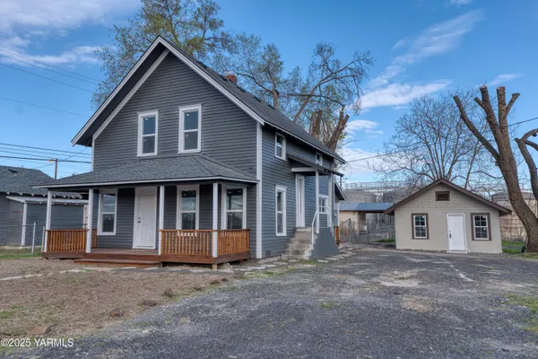 a view of a house with a yard and large tree