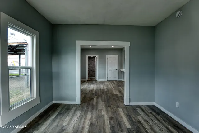 a view of an empty room with wooden floor and a window