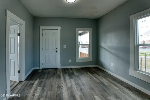 an empty room with wooden floor and windows