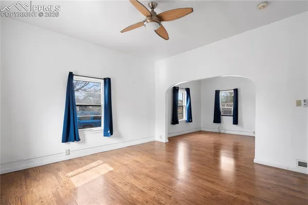 a view of an empty room with wooden floor and a window